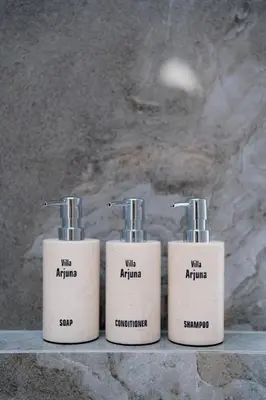 three white bottles sitting on top of a counter at Arjuna Villa in Seminyak