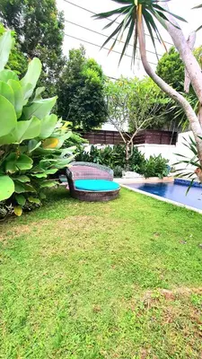 a backyard with a pool and a table and a chair at Villa Umah JD Umalas 3 kamar private pool in Canggu