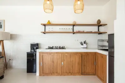 a kitchen with wooden cabinets and white walls at Homey Villa 2BR Seminyak in Seminyak