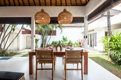 an outdoor dining room with a wooden table and chairs at Homey Villa 2BR Seminyak in Seminyak