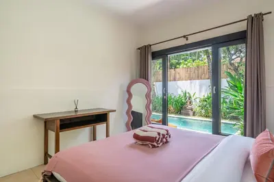 a bedroom with a bed with a pink blanket and a window at Homey Villa 2BR Seminyak in Seminyak
