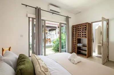 a bedroom with a white bed and a sliding glass door at Homey Villa 2BR Seminyak in Seminyak