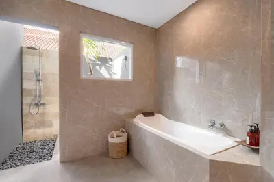 a bathroom with a tub and a shower with a window at Casa Amore Villa in Berawa Beach - Canggu in Canggu
