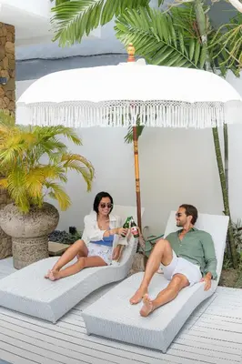 a man and a woman sitting on chairs on a porch at Casa Amore Villa in Berawa Beach - Canggu in Canggu