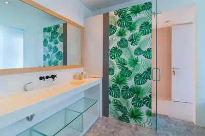 a bathroom with a sink and a glass shower door at Berawa -Ocean View 5 Bed, Walk to Beach, Sleeps 10 in Canggu