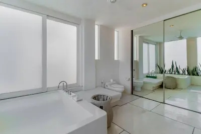 a bathroom with a tub and a toilet and a mirror at Berawa -Ocean View 5 Bed, Walk to Beach, Sleeps 10 in Canggu