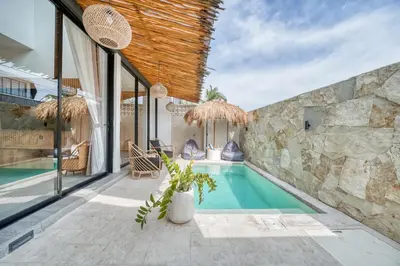 a swimming pool in a house with a stone wall at Tropical and Minimalist 2bd Umalas Villa with Private Pool in Canggu