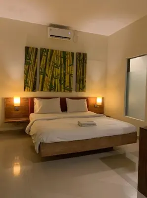 a bedroom with a bed with a painting on the wall at Marinos Place Legian in Legian
