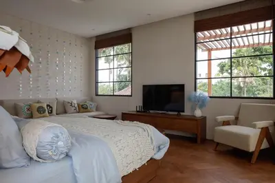 a bedroom with a bed and a tv and windows at Lavanya Villa Berawa beach in Canggu