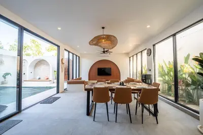 a dining room with a table and chairs and large windows at La Vilaya Villa in Kerobokan