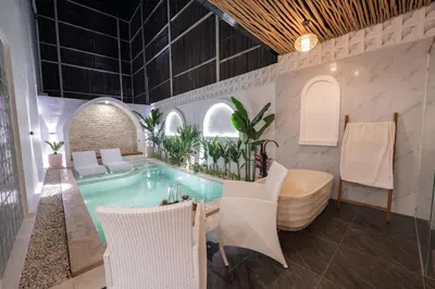 a pool in a room with chairs and a tub at La Vilaya Villa in Kerobokan
