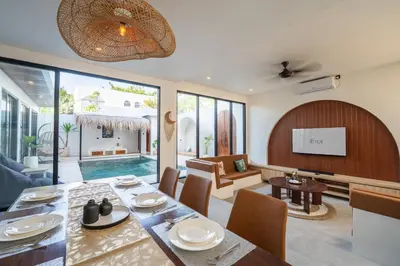 a dining room and living room with a table and chairs at La Vilaya Villa in Kerobokan