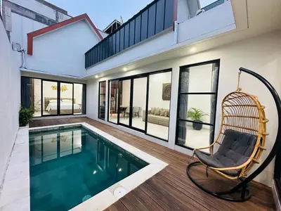 a house with a swimming pool and a chair at Athalia Villa Seminyak in Seminyak