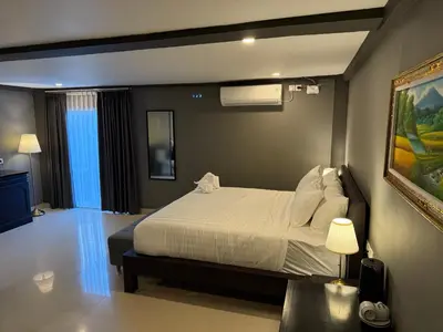 a bedroom with a white bed and a painting at Kooters Guesthouse Bali in Legian