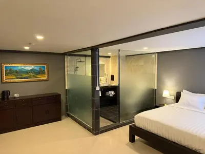 a bedroom with a glass shower and a bed at Kooters Guesthouse Bali in Legian