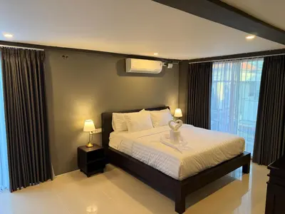a bedroom with a bed with two lamps and windows at Kooters Guesthouse Bali in Legian