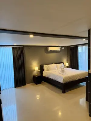 a bedroom with a bed and two lamps and windows at Kooters Guesthouse Bali in Legian