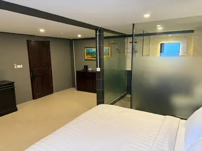 a bedroom with a bed and a glass shower at Kooters Guesthouse Bali in Legian