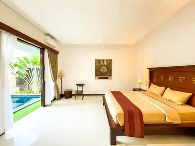 a bedroom with a large bed and a swimming pool at Ratu Deandra Villa Seminyak in Seminyak