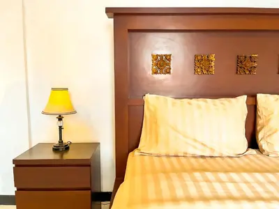 a bed with a wooden headboard and a table with a lamp at Ratu Deandra Villa Seminyak in Seminyak