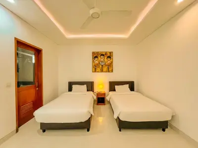 two beds in a room with white walls at Jasmine Villa in Nusa Dua