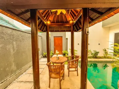 a patio with a table and chairs and a swimming pool at Jasmine Villa in Nusa Dua