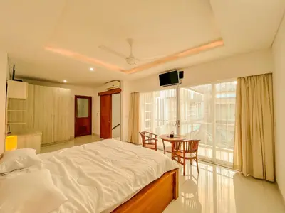 a bedroom with a bed and a table and a window at Jasmine Villa in Nusa Dua