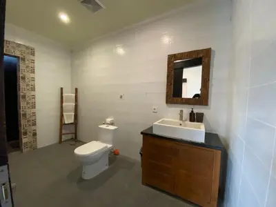 a bathroom with a toilet and a sink and a mirror at Sirkus Guesthouse in Canggu