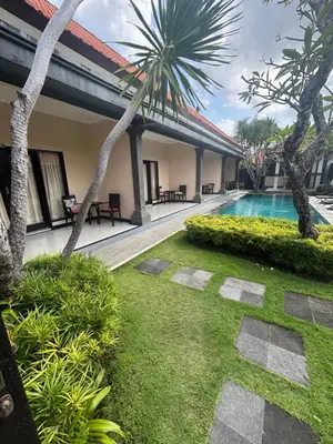a resort with a swimming pool and palm trees at Sirkus Guesthouse in Canggu