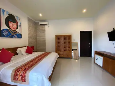 a bedroom with a bed and a painting on the wall at Sirkus Guesthouse in Canggu