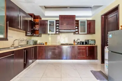a kitchen with wooden cabinets and a stainless steel refrigerator at Aileen 4 BR Private Pool Villa in Seminyak
