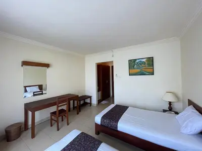 a hotel room with two beds and a desk at Puri Samaritan in Denpasar