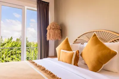 a bedroom with a bed with yellow pillows and a window at Anatari 3 BR Private Pool Villa in Seminyak