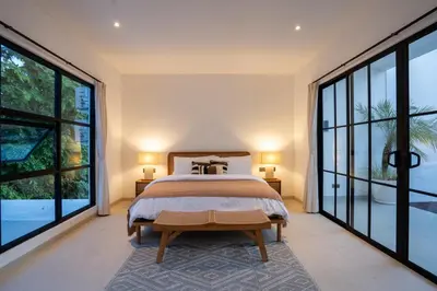 a bedroom with a large bed and large windows at Leva Villa - Luxury 3BR Jimbaran in Jimbaran