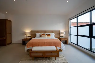 a bedroom with a bed and a large window at Leva Villa - Luxury 3BR Jimbaran in Jimbaran