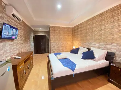 a bedroom with a bed and a tv on a brick wall at ABI Hotel3 - 1 minute to the Beach and 1 second to the Mall in Ngurah Rai International Airport
