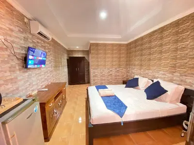 a bedroom with a bed and a tv on a brick wall at ABI Hotel3 - 1 minute to the Beach and 1 second to the Mall in Ngurah Rai International Airport