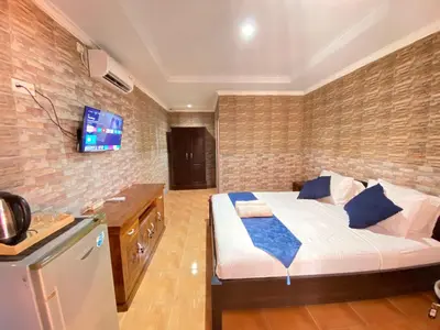 a bedroom with a bed and a tv on a brick wall at ABI Hotel3 - 1 minute to the Beach and 1 second to the Mall in Ngurah Rai International Airport