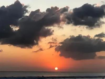 a sunset on the beach with the sun in the sky at Apartemen 6236 at Jayakarta Residence Bali in Seminyak