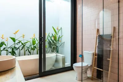 a bathroom with a tub and a toilet and a window at Tropical Chic Villa w Rooftop & Pool in Seminyak in Seminyak