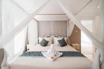 a bedroom with a bed with white sheets and pillows at D Villa Seminyak in Seminyak