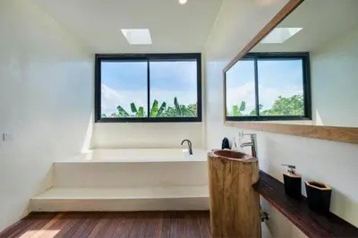 a bathroom with a bath tub and two windows at Quilon 2 BR Private Pool Villa in Seminyak