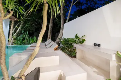 an outdoor seating area with trees and a swimming pool at Villa Lalalax 3BR Tropical Retreat in Jimbaran in Uluwatu