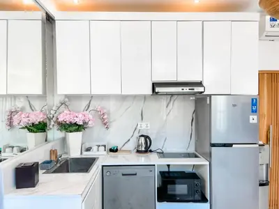 a white kitchen with white cabinets and pink flowers at Villa Diah in Seminyak