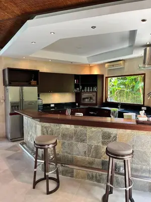 a kitchen with a bar with two stools at Bumahan Villa in Seminyak