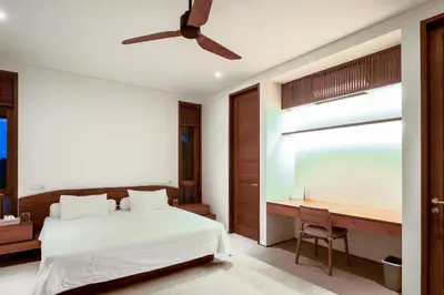 a bedroom with a bed and a desk and a ceiling fan at Bali Radiance 4 bedrooms with private bathrooms - Pool, Beach & Airport in Ngurah Rai International Airport