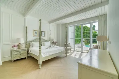 a white bedroom with a bed and a large window at Colonial House 4BR Villa With Ocean View in Berawa in Canggu