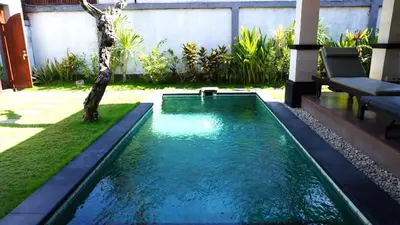 a swimming pool in a backyard with a tree at Tahoma Villas Seminyak by ABM in Seminyak