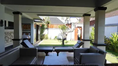 a screened in porch with chairs and a table at Tahoma Villas Seminyak by ABM in Seminyak