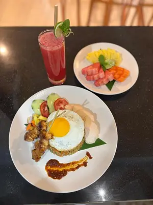 two plates of food on a table with a drink at Casa Benoa Homestay in Nusa Dua